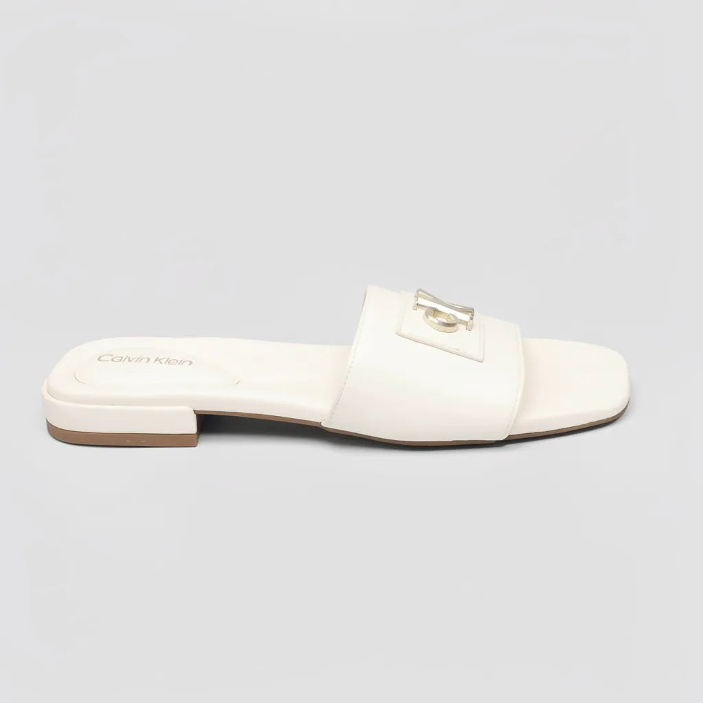 Calvin Klein Sandalia Slip On Blanco hueso Placa Dorado Empeine Suela Blanca/ café | Photo Studio AI | 1